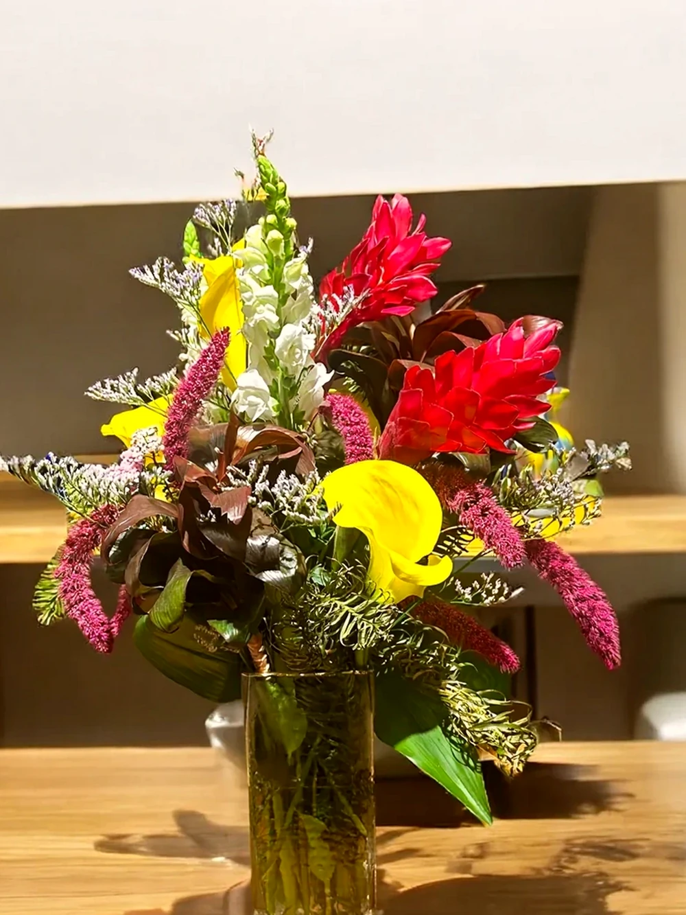 Arranjo Floral Tropical com Callas Amarelas e Alpínias no Vaso de Vidro Retangular